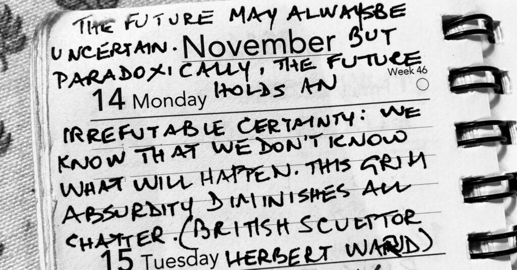 A black and white photograph of a small notebook with a handwritten quote on Monday the 14th of November. "The future may always be uncertain. But paradoxically, the future holds an irrefutable certainty: we know that we don't know what will happen. This grim absurdity diminishes all chatter." (British sculptor Herbert Ward)