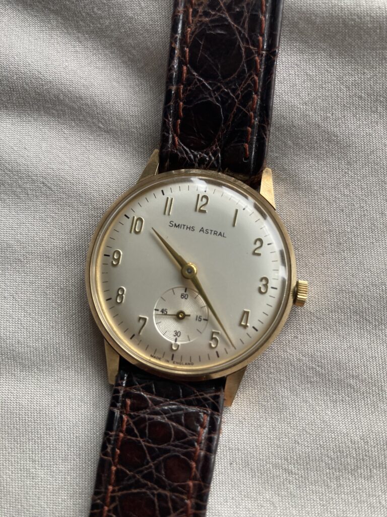 The gold and white dial of a Smiths Astral wristwatch.