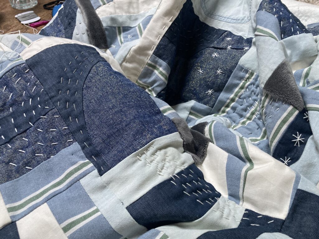 A rumpled quilt of blue squares with visible white stitching.