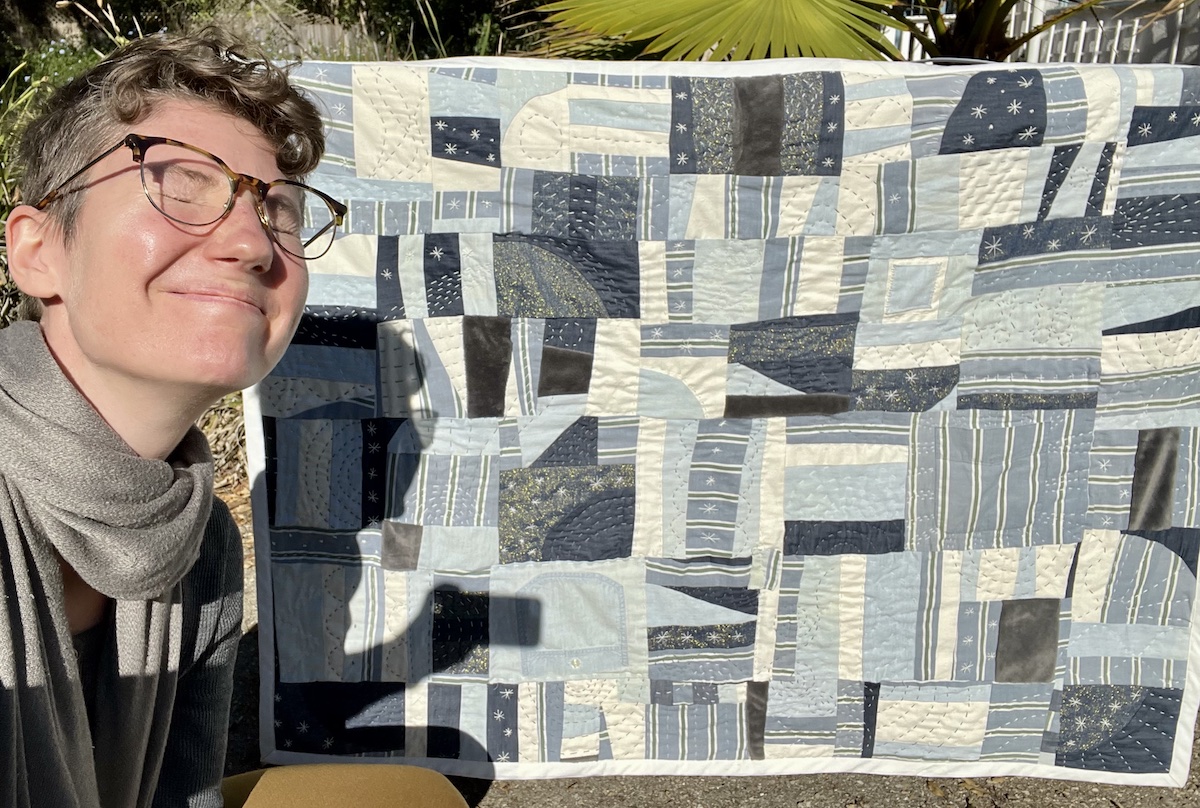 Lucy smiling in front of her finished quilt