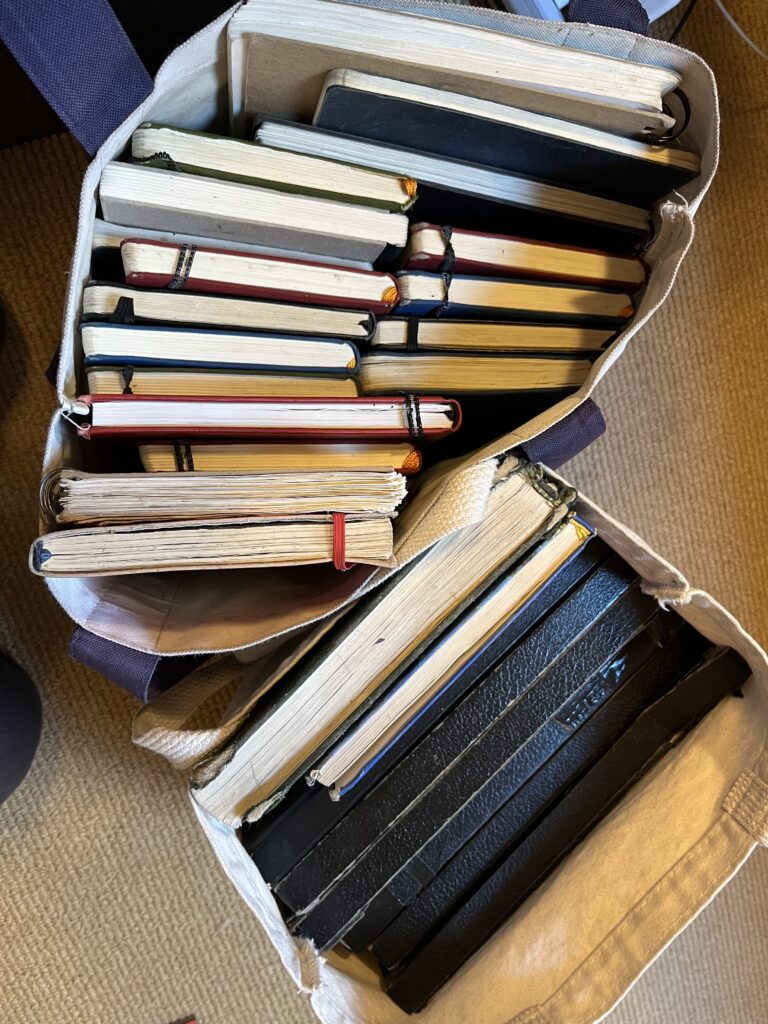 Two tote bags full of sketchbooks